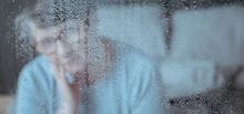 Elderly patient behind rain-spattered window